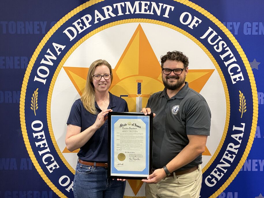 Utilities Commission Chair Sarah Martz and Attorney General's Office attorney Jacob Larson present a proclamation signed by the governor.